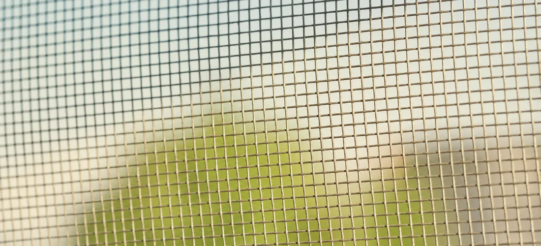 Macro of the mesh weave against the light, a blurred garden beyond