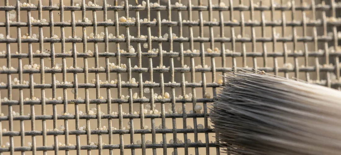 Grains of sand caught in the weave and the tip of a brush