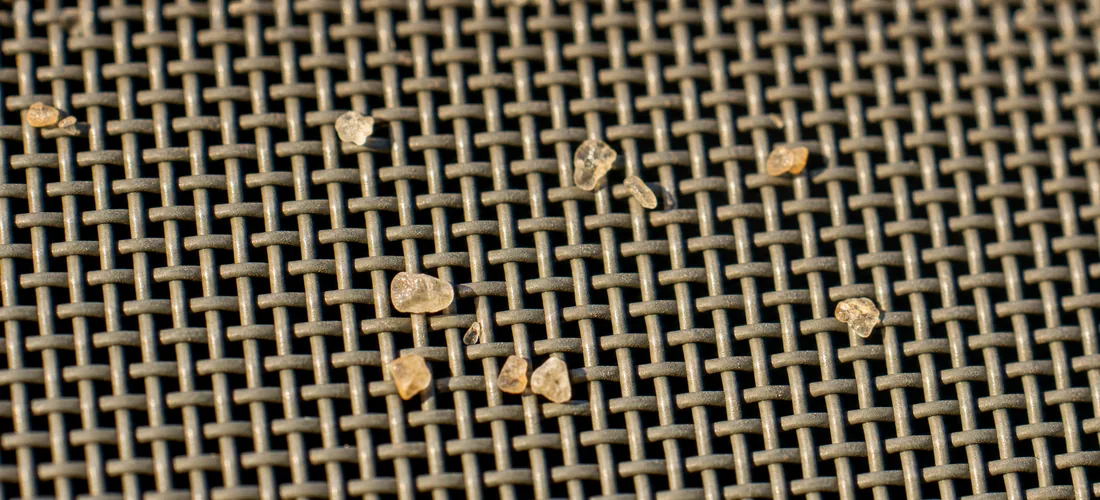 Macro of the anti-sand weave with grains resting on the strands