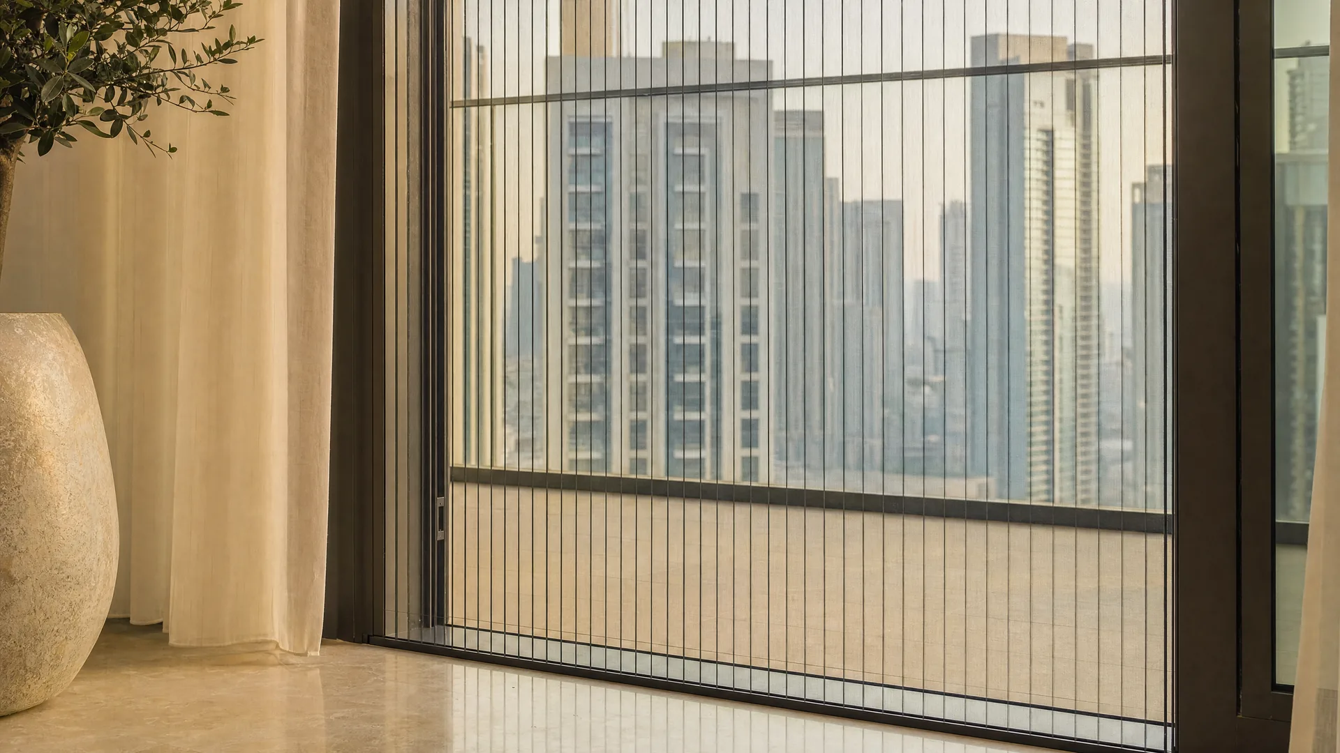 A pleated screen on a high-rise balcony door with towers beyond